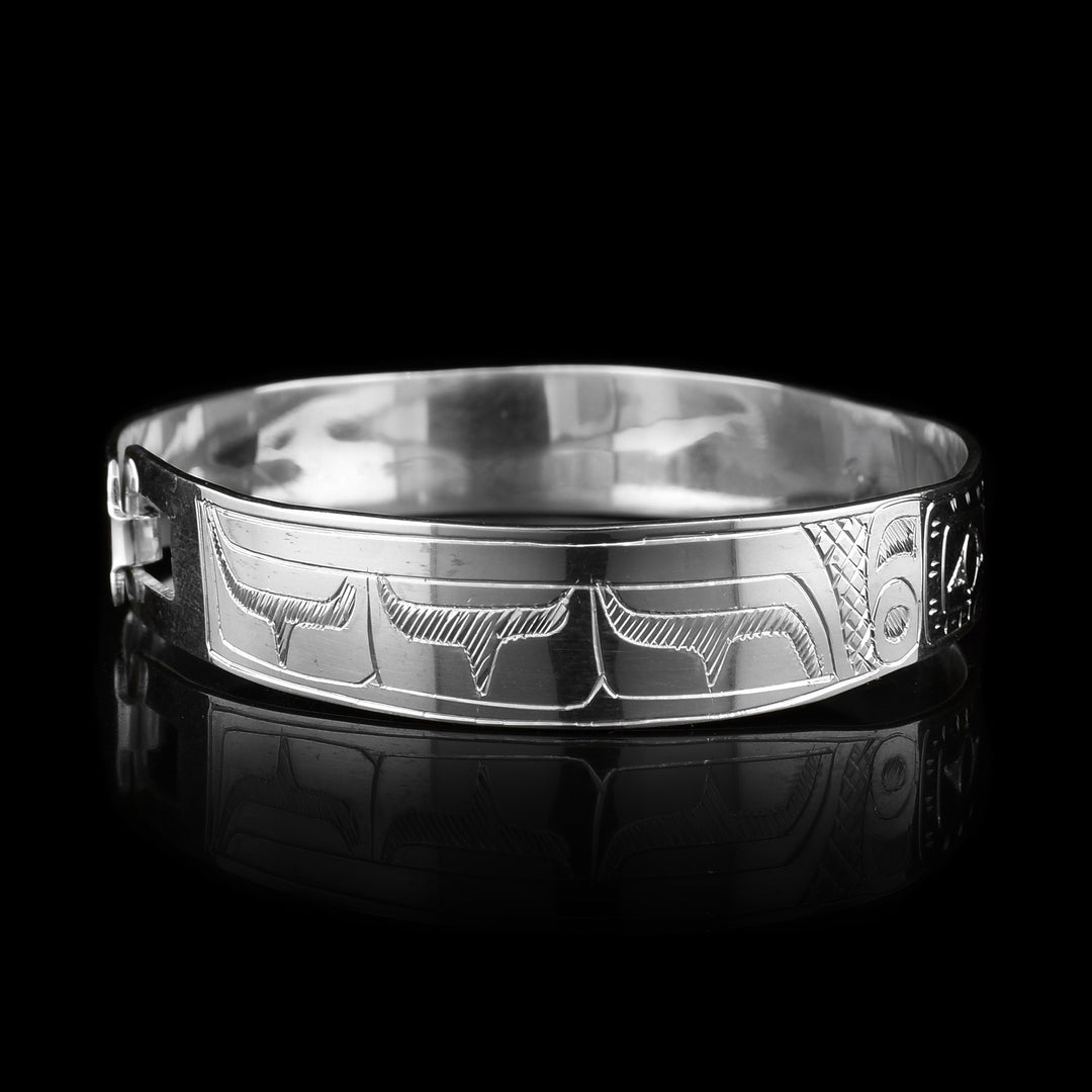This Hummingbird and flower bracelet has a single, sterling silver band with a clasp in the back. There are two depictions of the Hummingbird carved into the band. The legends are depicted facing each other and there are flowers carved in the center of it.