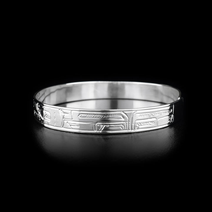 This sterling silver bracelet has depictions of the Hummingbird, the Bear, and the Sun carved into the band. The Sun is depicted at the top of the bracelet and there is a clasp in the back.