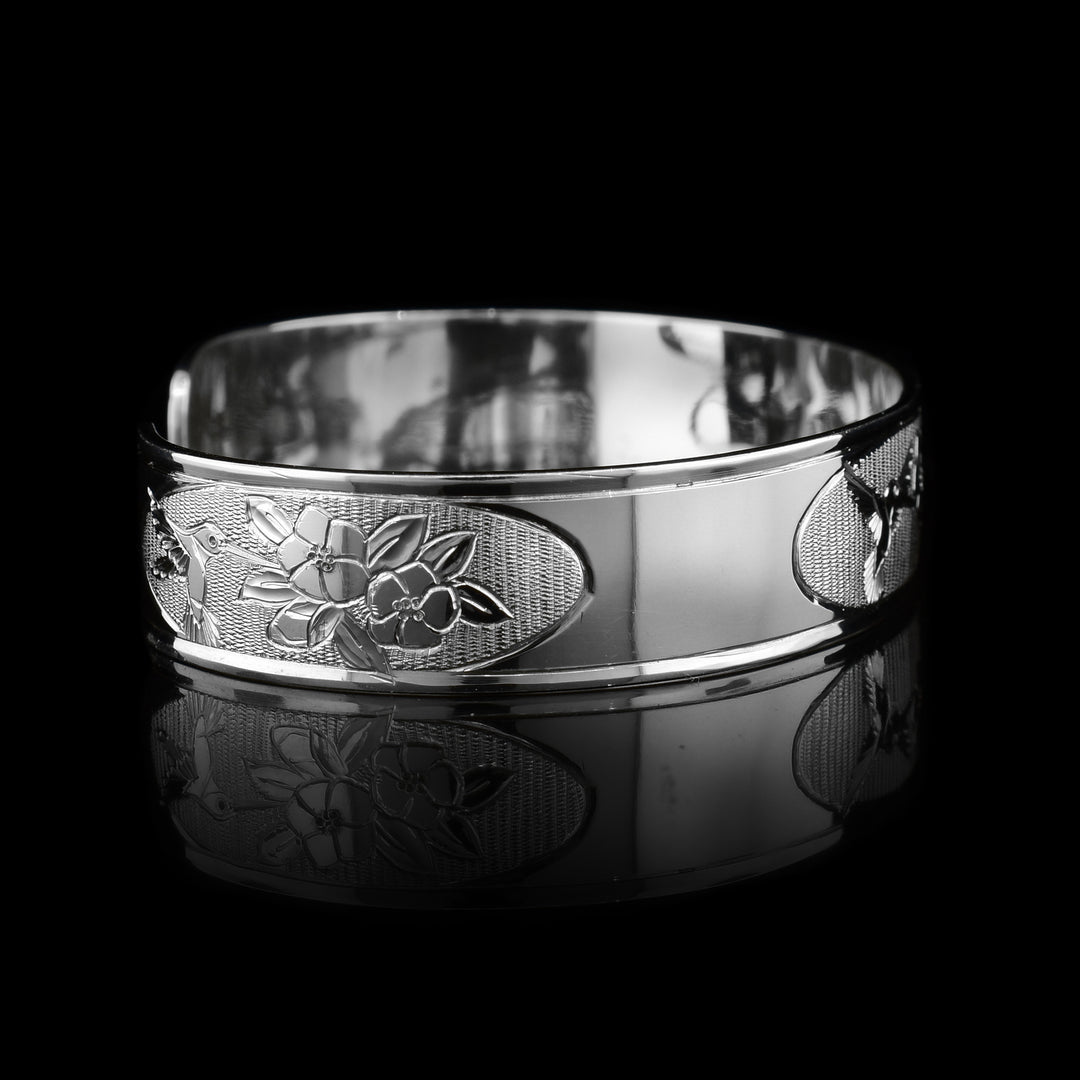 This Hummingbird with flower bracelet has a thin, sterling silver band with a gap in the back. There is a depiction of a hummingbird flying in front of rose flowers.