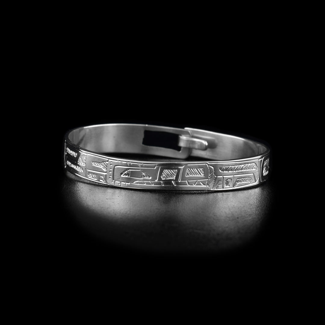 This baby sterling silver bracelet has a single, thin band with a clasp in the back. There is a full body depiction of the Wolf carved into the band at a side profile. Its head is at the front of the band and its body wraps around the length of the band.