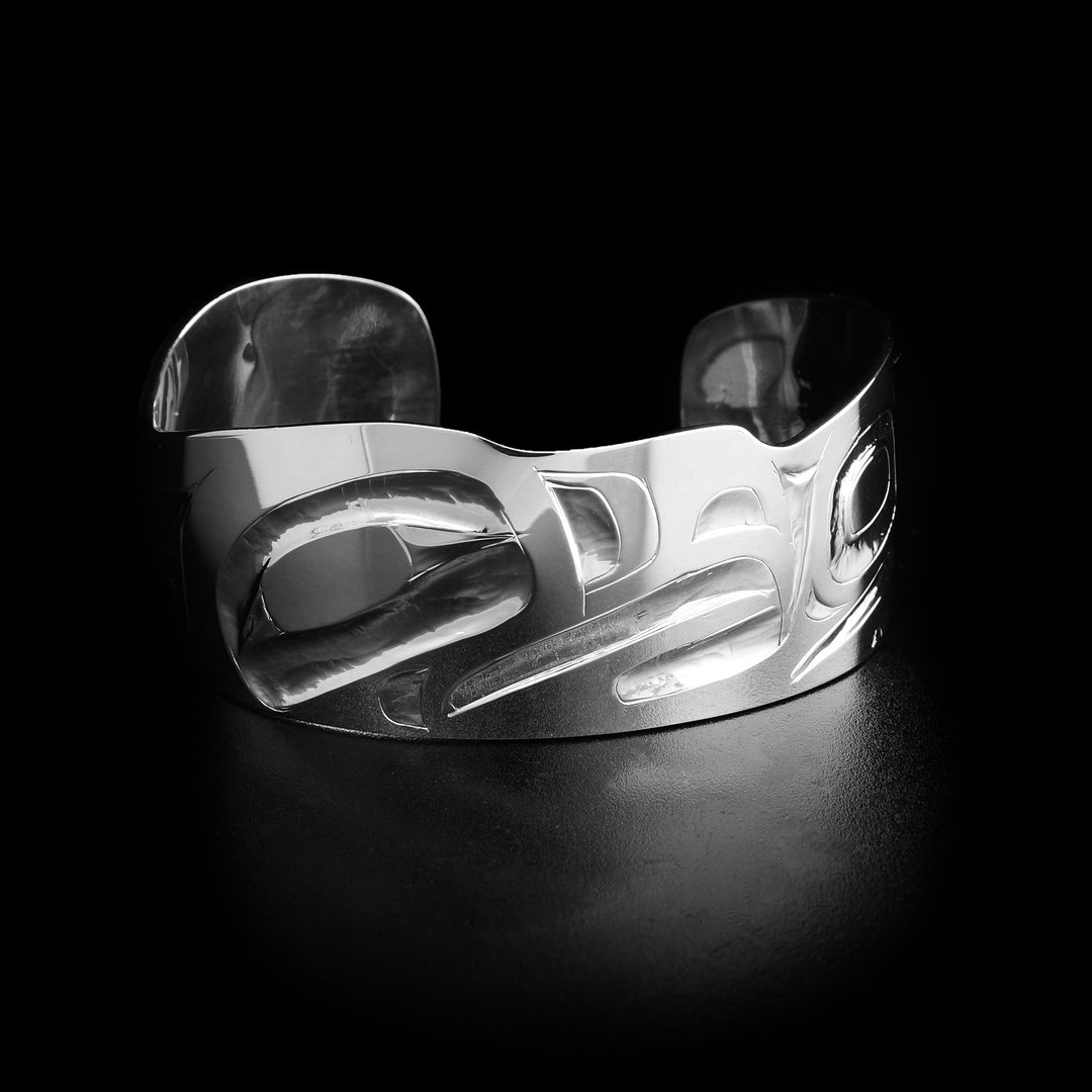This wide cuff bracelet has the head of an eagle facing the right in the center of the bracelet. The top of the bracelet isn't linear and instead is a wave-like pattern.