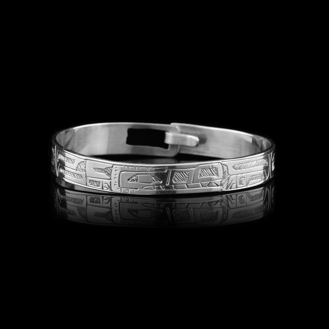 This baby's silver bracelet is made form sterling silver and has a single band with a clasp in the back. There is a depiction of the Orca carved into the band. The head is in the center of the band with the details of its body spanning across the band.