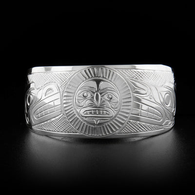 This silver cuff bracelet depicts the moon in the center with the head of a wolf to its right and the head of a bear to its left. The background is cross-hatched.