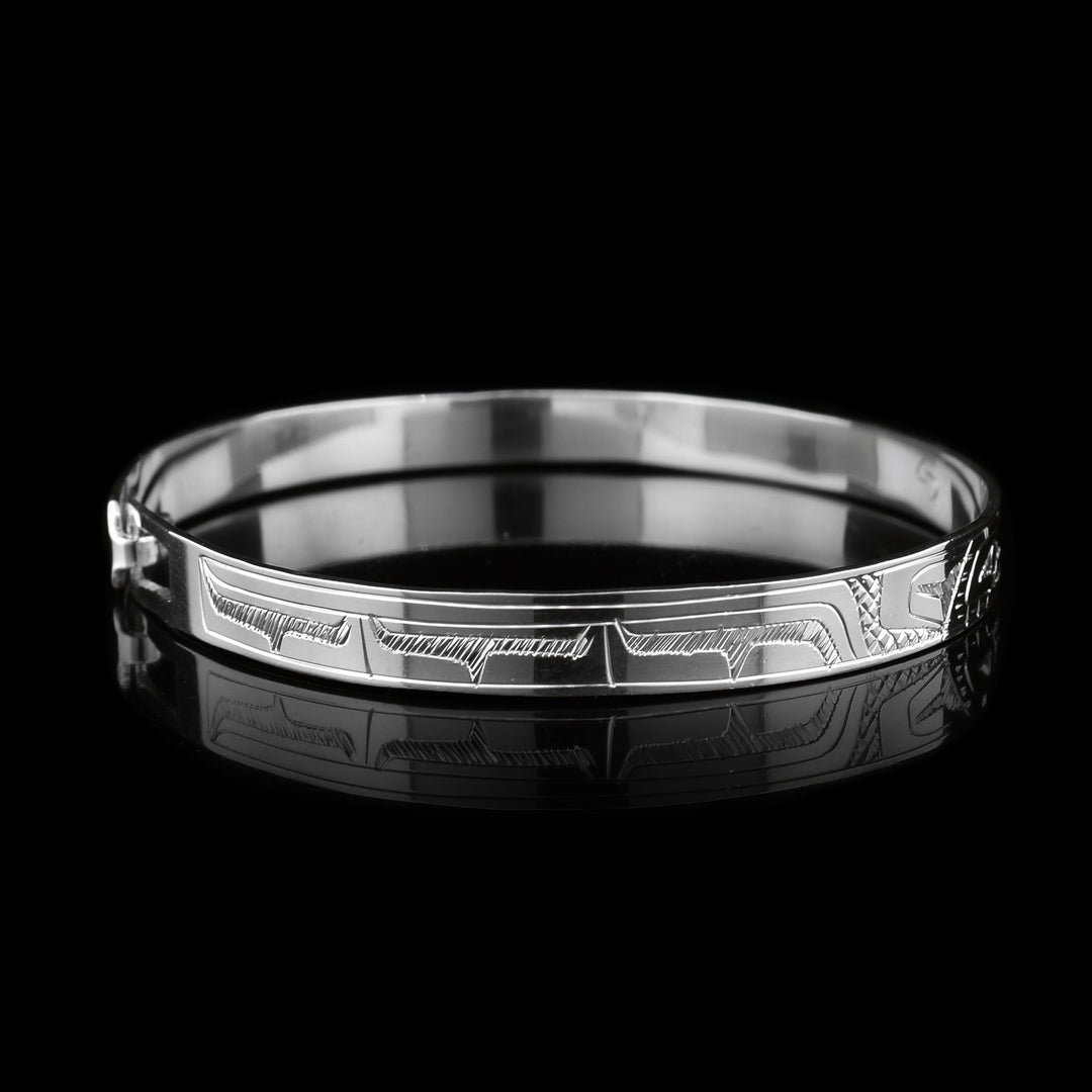 This dainty Eagle and Hummingbird bracelet has a thin, sterling silver band with a clasp in the back. There are depictions of the Eagle and the Hummingbird carved into the surface of the band. The legends are depicted facing each other. 