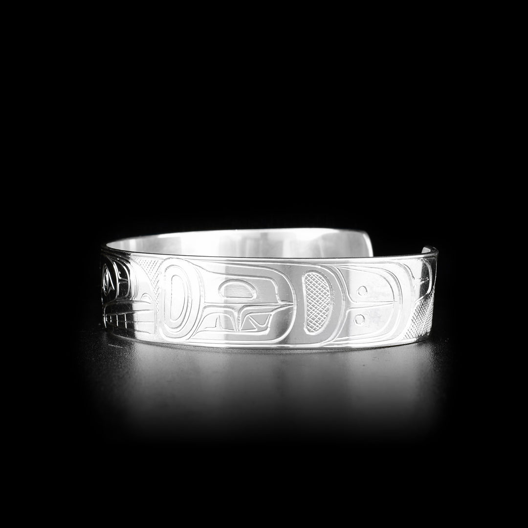 This sterling silver bangle bracelet has a single band with a gap in the back with two depictions of the Orca carved into the surface of the band.