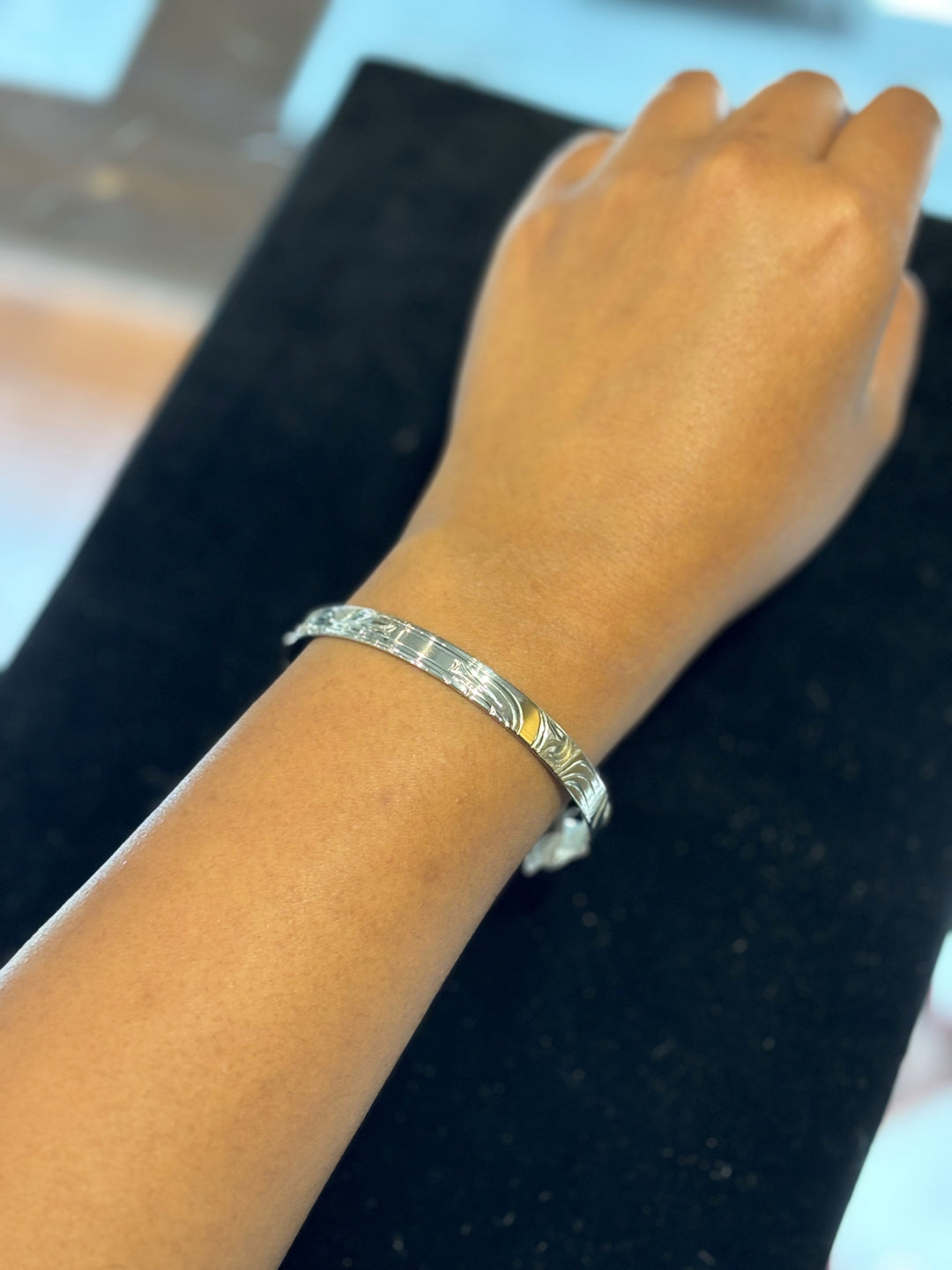 The photo shows the model wearing the thin cuff bracelet on their wrist. The model's arm and hand is shown.