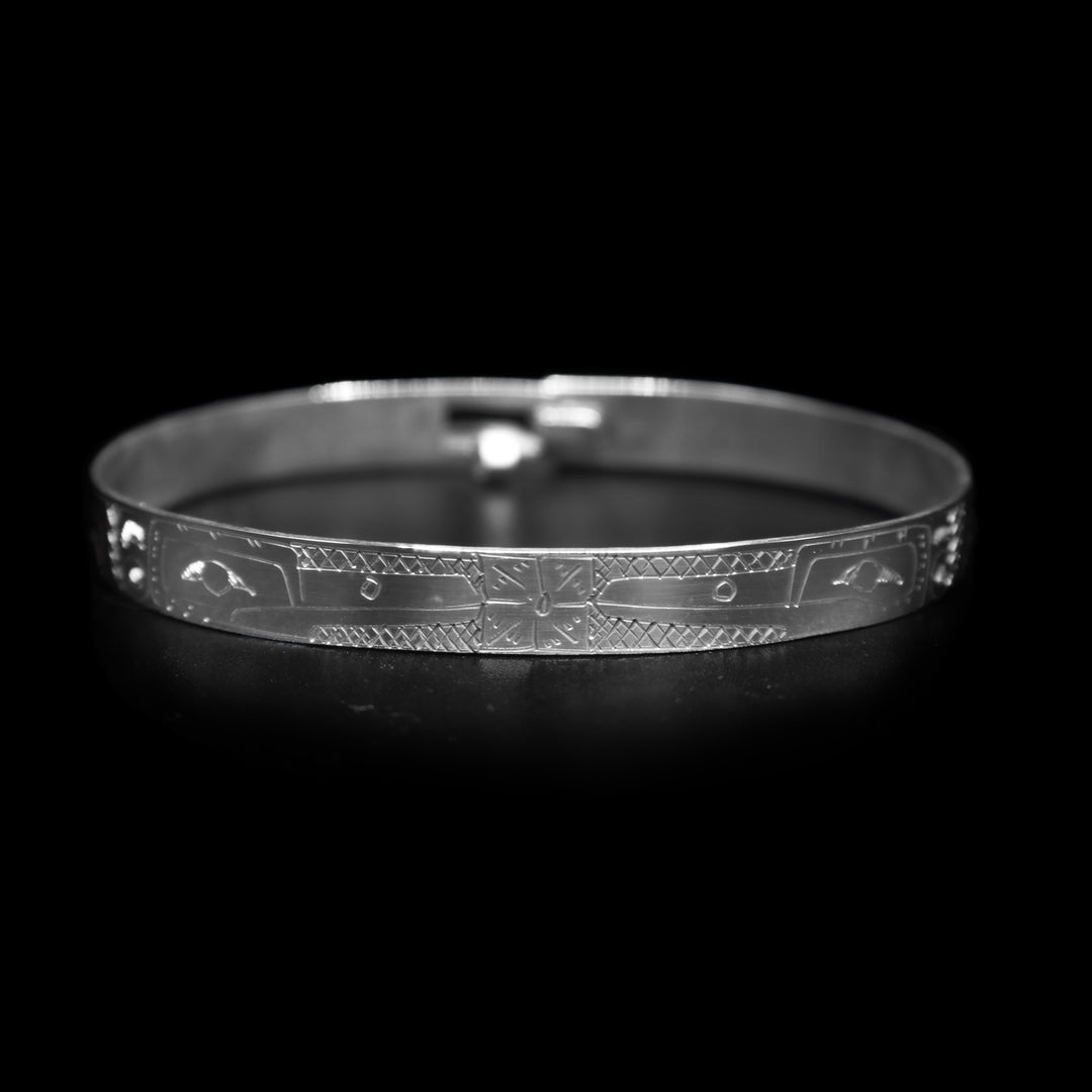 This large bangle Hummingbird bracelet has a thin, sterling silver band with a clasp in the back. There are depictions of the Hummingbird facing each other carved into the piece. There is also a flower carved into the center of the piece.