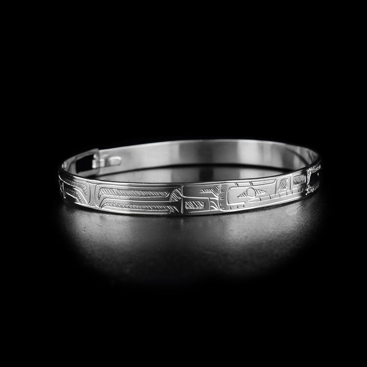 This thin bangle bracelet has a single, thin band made from sterling silver with a clasp in the back. There are depictions of the full body of the Hummingbird and Wolf legends carved into the piece at a side profile. The faces of the legends meat at the top of the band.