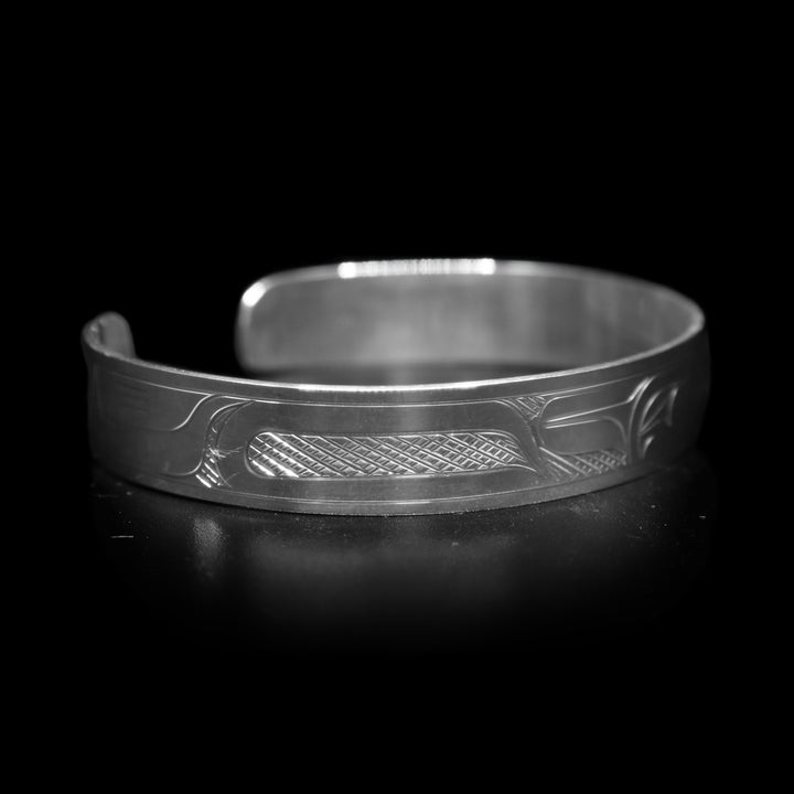 This Raven bracelet has a single, sterling silver band with a gap in the back. There is a depiction of the Raven carved across the surface of the band and a small Sun carved in the side of the band.