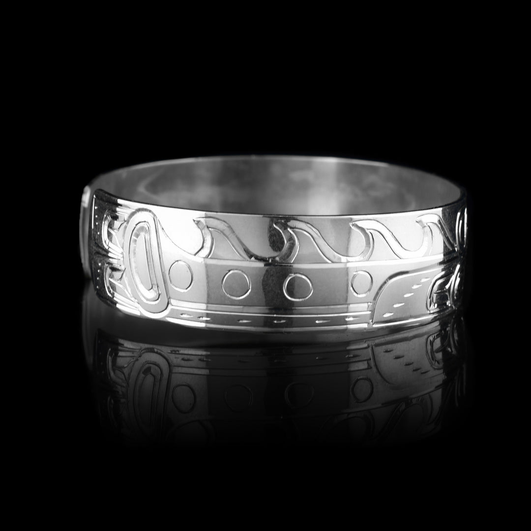 This sterling silver cuff bracelet has a single band with a depiction of the Sisiutl which is an indigenous sea serpent that has been carved into the surface of the band. The head of the serpent is in the center and around the band there is a serpent body with ridges on the top of it.
