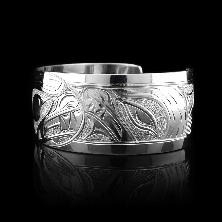 This stunning Bear bracelet is made using sterling silver and has a single, wide band with a gap in the back. There are intricate carvings on the surface of the piece that depicts the Baby Bear in the womb and being watched over by its mother who is depicted in silver and carved on the side of the piece. On the other side of the band, there are depictions the claws of the Bear.