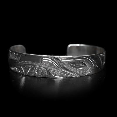 This dainty bracelet cuff has a thin, sterling silver band with a gap in the back. There is a depiction of the Raven in the night sky with the Moon legend and stars etched into the band.