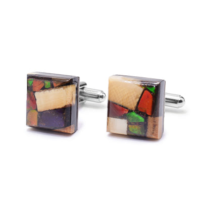 These ammolite cufflinks have a square shaped and are made by encasing chunks of ammolite and mammoth ivory in resin. The ammolite has green and red colours. The cufflinks are set on stainless steel backs.