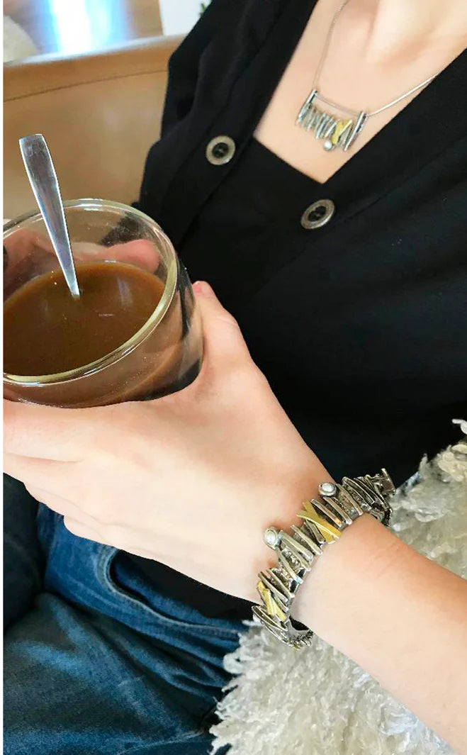 This photo shows the bracelet worn on a model. She is holding a glass of coffee and the bracelet can be seen.