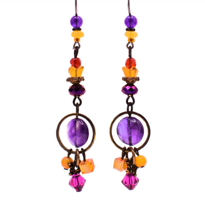 These amethyst dangle earrings are long and narrow and are made up of primarily purple, yellow, red, and orange stones. A round amethyst is located with brass around it near the end of each earring.