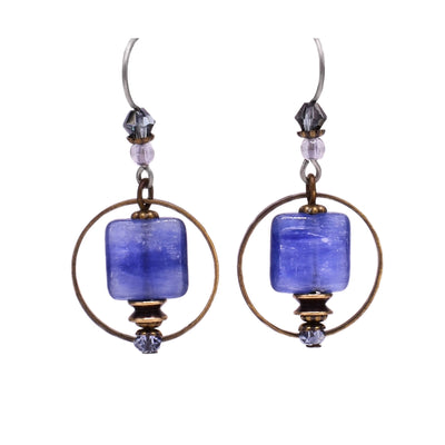 These kyanite earrings feature a square kyanite with a large, circular brass accent behind the kyanite. Above the kyanite is a black Swarvoski crystal and a clear glass bead. Below is a light blue faceted glass bead with more brass accents.