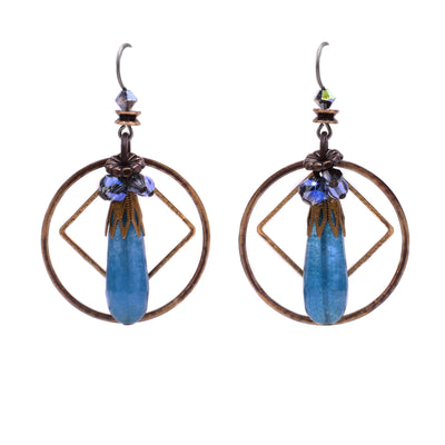 These raindrop earrings feature blue quartz in the shape of a raindrop in the center with glass and crystal beads clustered above. Behind the quartz is a diamond-shaped brass accent and a larger circular brass accent.