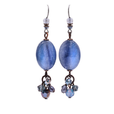 These dangle earrings depict an oval blue kyanite in the center with blue glass beads and pearls attached as a cluster to the bottom. Above is a round glass bead along with an Austrian crystal bead.