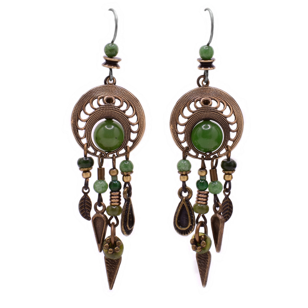 These jade earrings feature a circular, uniquely carved brass encasing a jade bead. Hanging from the brass are 4 strands with varying lengths that have green beads and large brass accents such as a feather, arrows, and a raindrop attached.