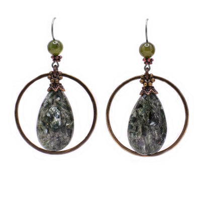 These teardrop earrings feature a teardrop green seraphanite stone in the center with a large, circular brass accent around it. Above is small green jade bead.