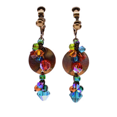 These clip earrings feature a round brass accent in the back with a string of multi-coloured Swarovski crystals, glass beads, and carnelian agate hanging in front. At the bottom is a large, blue crystal bead.