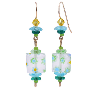 These glass earrings feature a rectangular, clear glass as the centerpiece with flowers on it. Attached to the top and bottom of each earring are glass flowers in varying colours. At the very top is a yellow crystal.