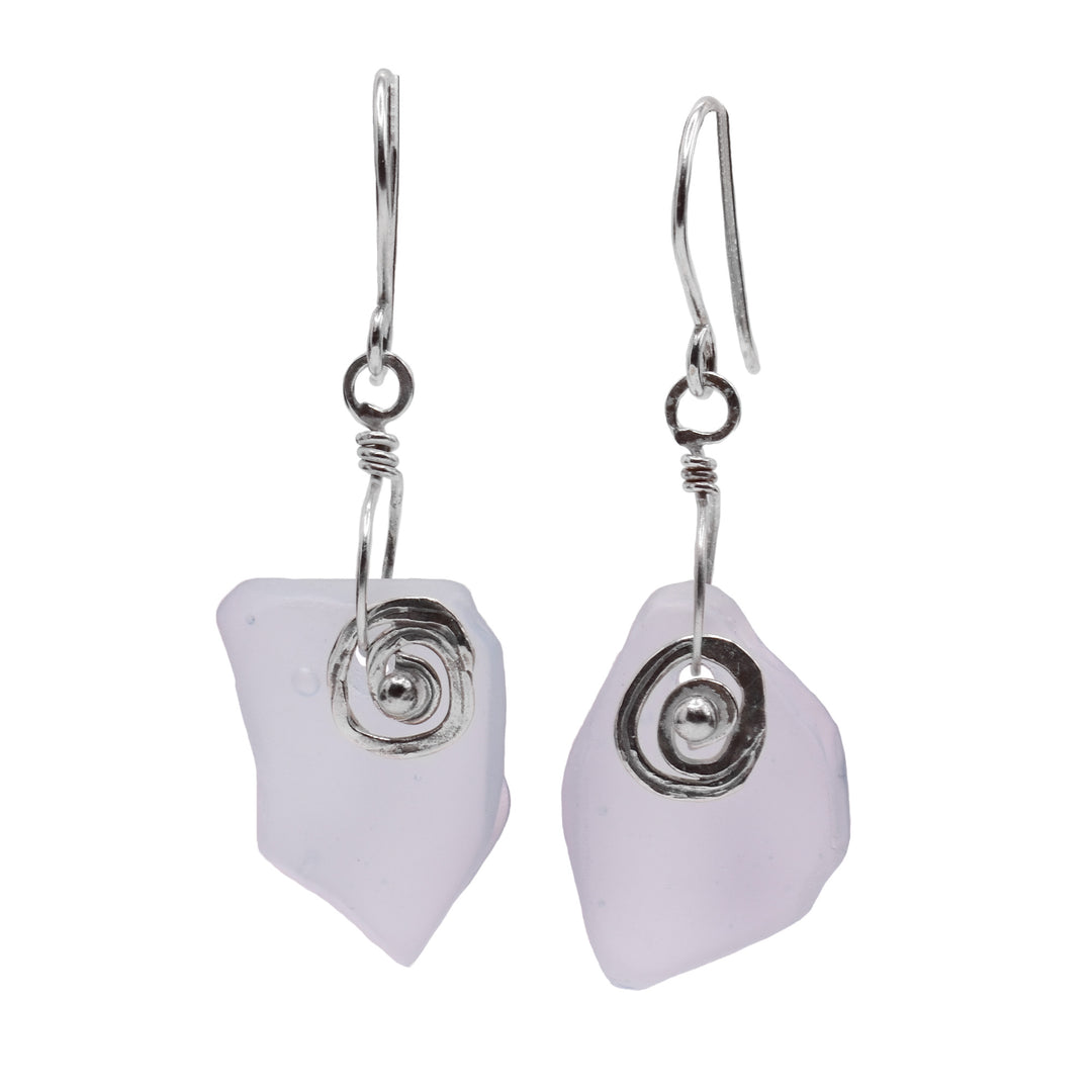 These dangling sea glass earrings have misshapen sea glass hangs with a sterling silver charm in front of them. The silver charm has a spiral shaped representing a snail shell. 