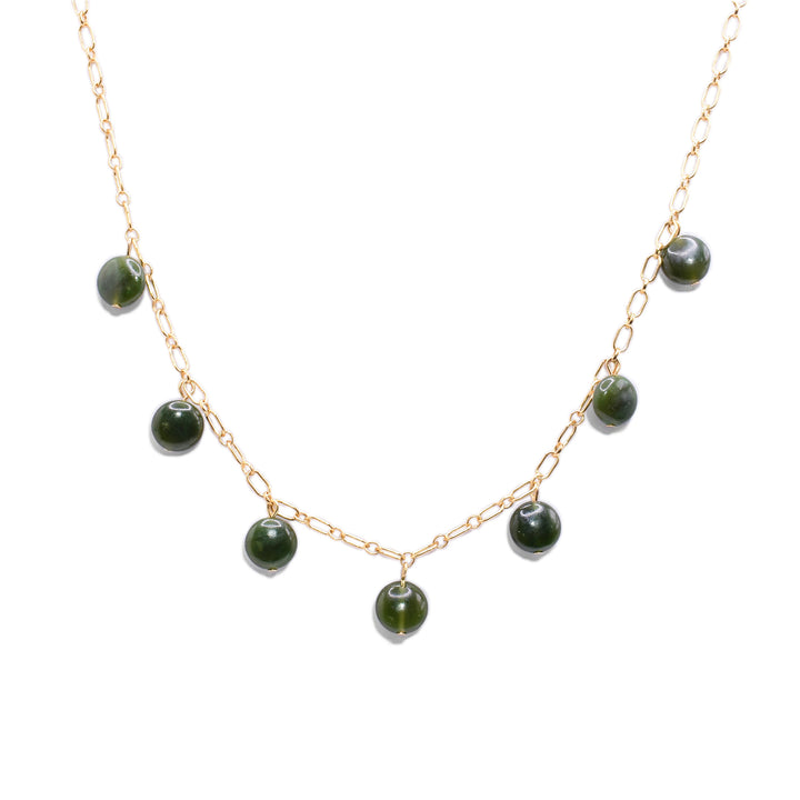 This jade charm necklace has a simple 14K gold filled chain with 7 jade beads at the bottom half of the piece. The jade charms are small, circular and flat.