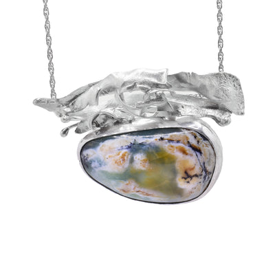 This Peruvian opal necklace has an assymetrical oval-shaped Peruvian opal as the centerpiece with an abstract arrangement of sterling silver accents above it. The chain is attached at each end of the silver adornment.