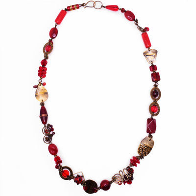 This necklace is a colourful red piece with multiple differents shapes made from glass, garnet, pearl, and handworked brass.