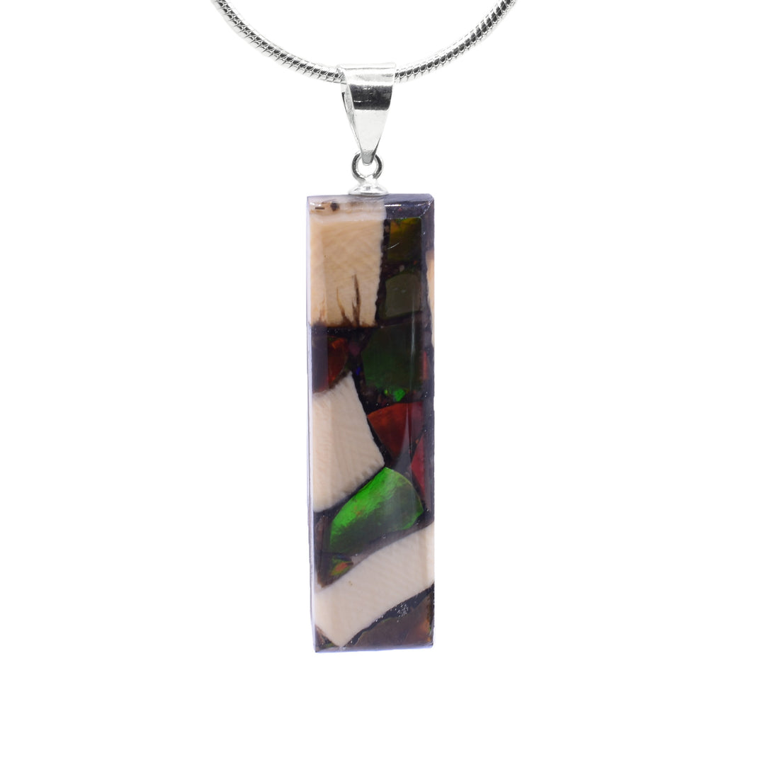 This unique ivory pendant is made from fossilized mammoth ivory, ammolite gemstones and sterling silver. The pendant is thin and rectangular and is made by casting pieces of ivory and ammolite together. The jump ring is made from sterling silver.