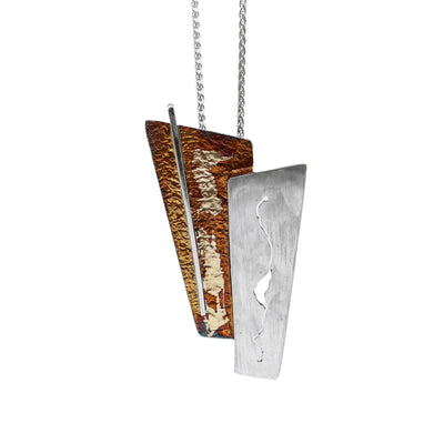 This oxidized silver necklace has two trapezoid-shaped pieces put together; one silver and the other varying colours of orange and brown.