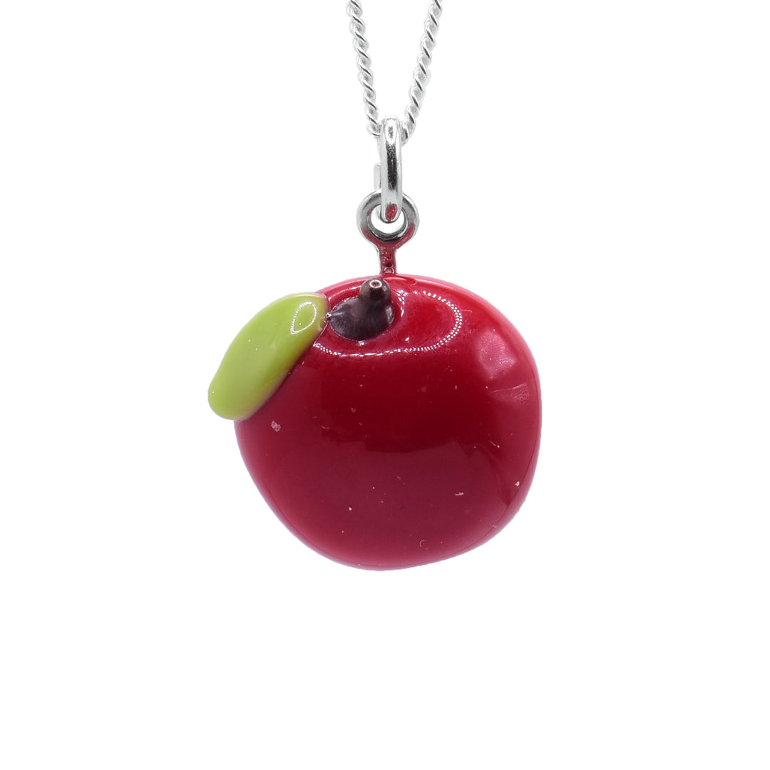 This apple necklace has a pendant made from lampworked glass. There is red glass shaped like an apple and a single, green leaf at the top. There is also a brown stem at the top of the piece.