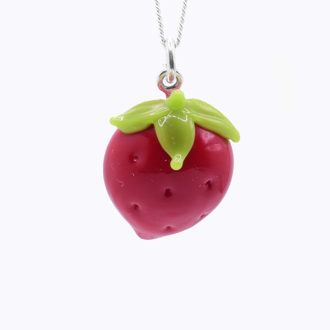 This strawberry necklace is made from lampworked glass and is strawberry shaped. There is red glass that is round and tapered at the bottom and green glass at the top that are four leaves and a small stem. There are dimples made across the surface of the red glass.