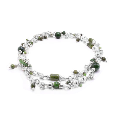 This jade long necklace has a Han made from circle shaped, sterling silver links and has cylinder and spherical shaped beads made from jade. There are small, jade beads that dangle from the chain.