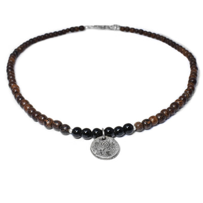 This wooden necklace has wooden beads and 5 black glass beads set on a cord with a sterling silver pendant.