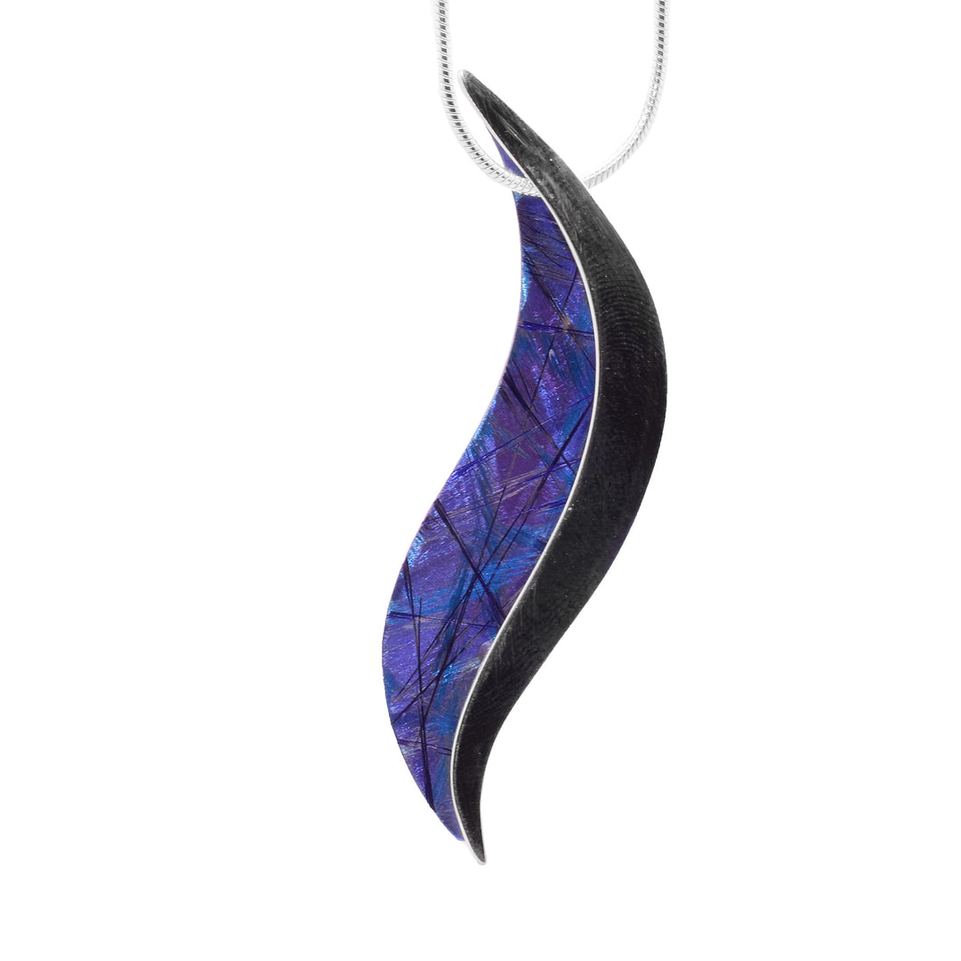 This titanium necklace is made from sterling silver and has blue, anodized titanium on it. The pendant is wavy and half is silver and the other half is titanium.