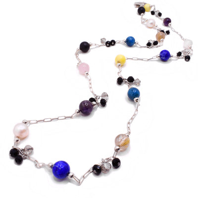 This multi gemstone necklace has a paperclip chain to which small clear and black crystals are attached evenly throughout. There are beads of many colours on the chain including pink, blue, black, yellow, clear, white, and purple.