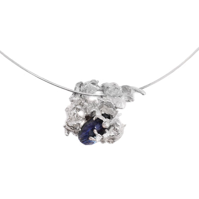This sapphire necklace has an oval, blue sapphire encased in an abstract shaped silver casing resting on an omega chain.