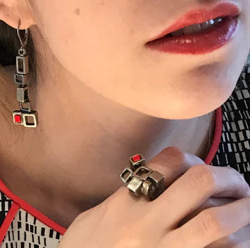 Shows bottom half of the model's face with the earrings in and her hand by her chin with a ring from the "Habitat" collection.