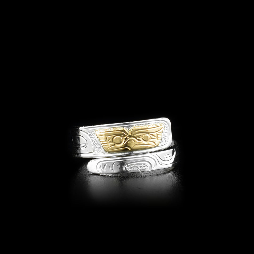 This sterling silver and 14K gold ring has a band that wraps around the finger twice. There are carvings across the band and a depiction of the Owl carved into it. The face of the Owl is made from 14K gold.