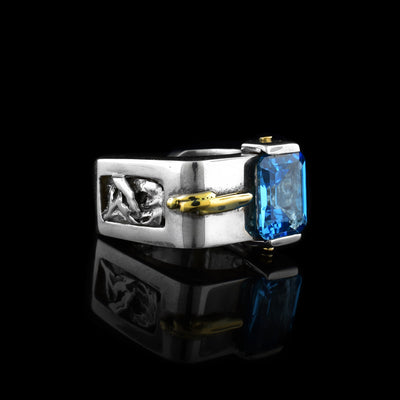 This sterling silver ring is square in shape and has a big square blue topaz stone in the front. There is a 14K gold detail to the side of the stone.