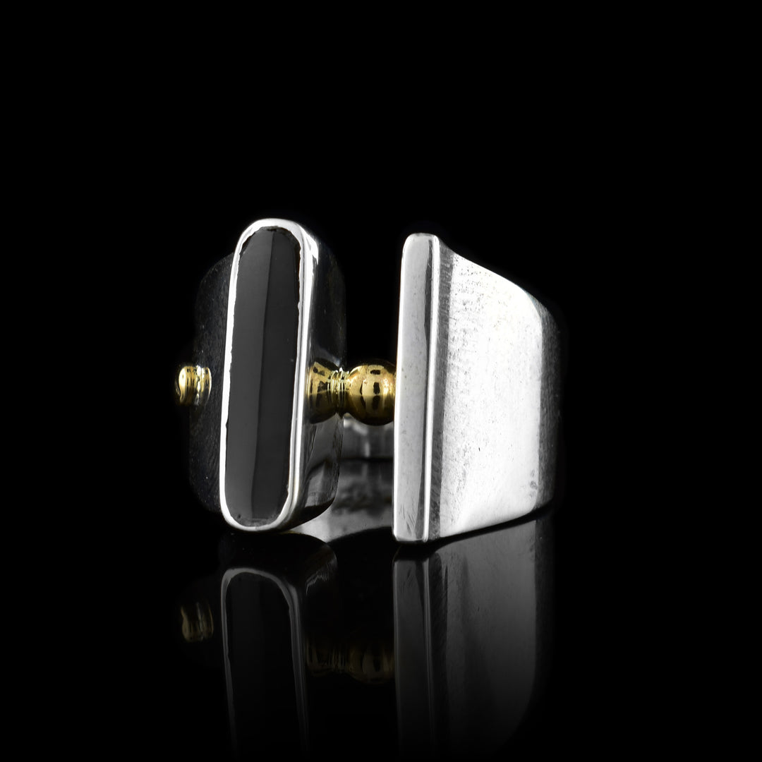 This sterling silver signet ring has a tapered band and a gap at the top of the ring. On the signet is a polished plexiglass embellishment and 14K rose gold studs.