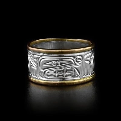 This bear ring has a silver band with the top and bottom encased in solid yellow gold border. The design depicts the head of a bear facing the right with designs representing its paws and body carved throughout the band.