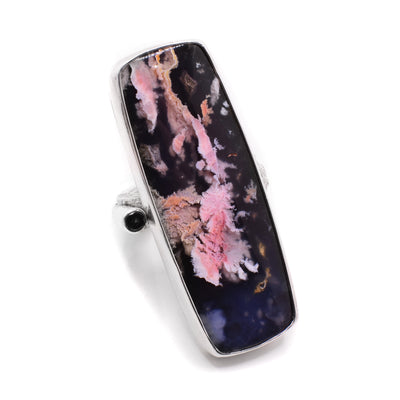 This agate ring has a rectangular shape with a dainty band behind and a small, black diamond to the side of the large agate. The agate is mainly black in colour with pink streaks.