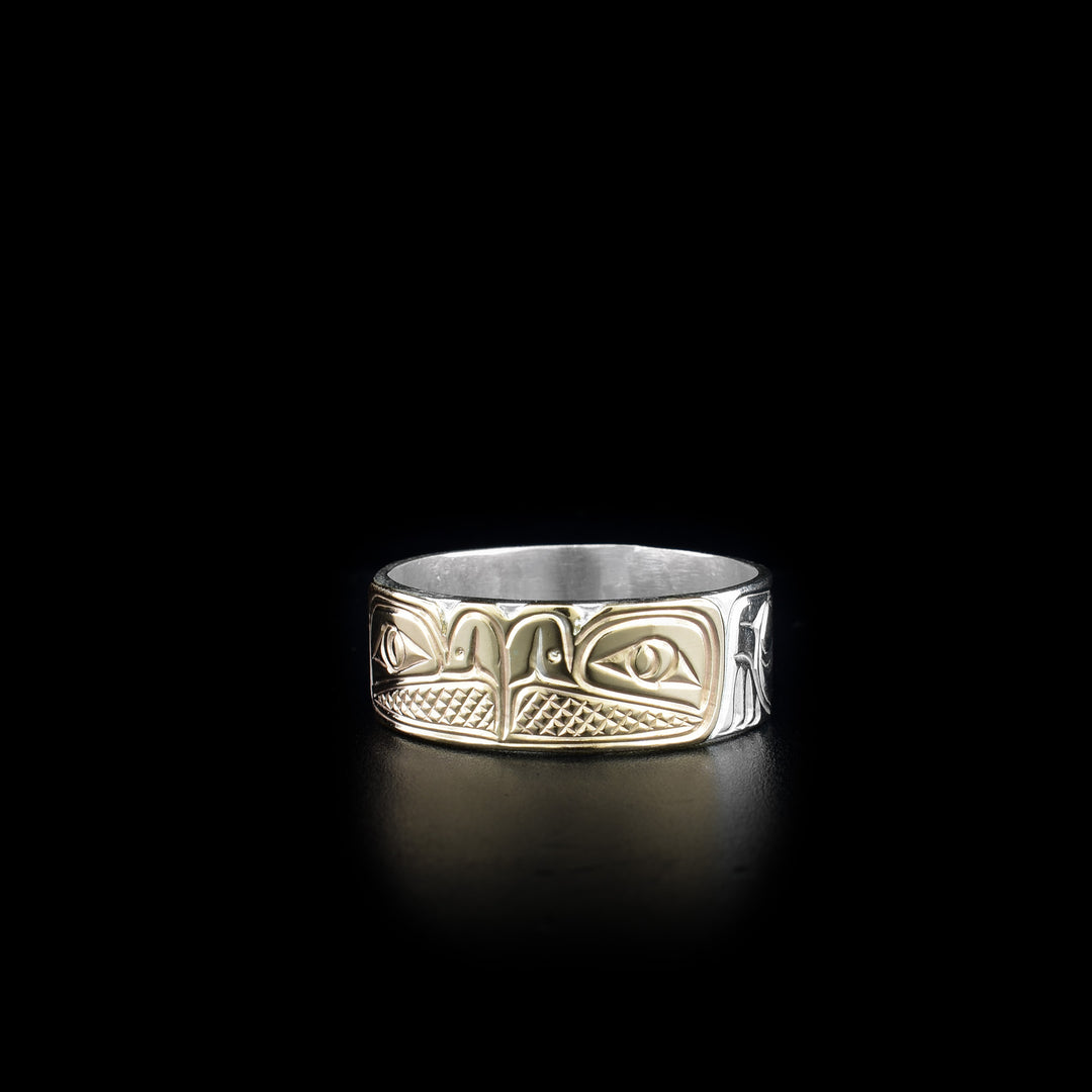 This sterling silver and 14K gold ring has two depictions of the Eagle carved into the surface of the band. The Eagles are depicted facing each other and their heads are made from 14K gold.