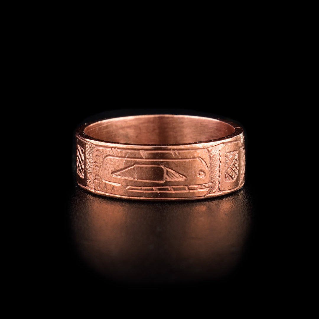 This Orca Ring has a single, copper band with a side profile depiction of the Orca carved into it. The head of the orca is show with its teeth and eyes included and there are cross hatching designs in the background of the scene.