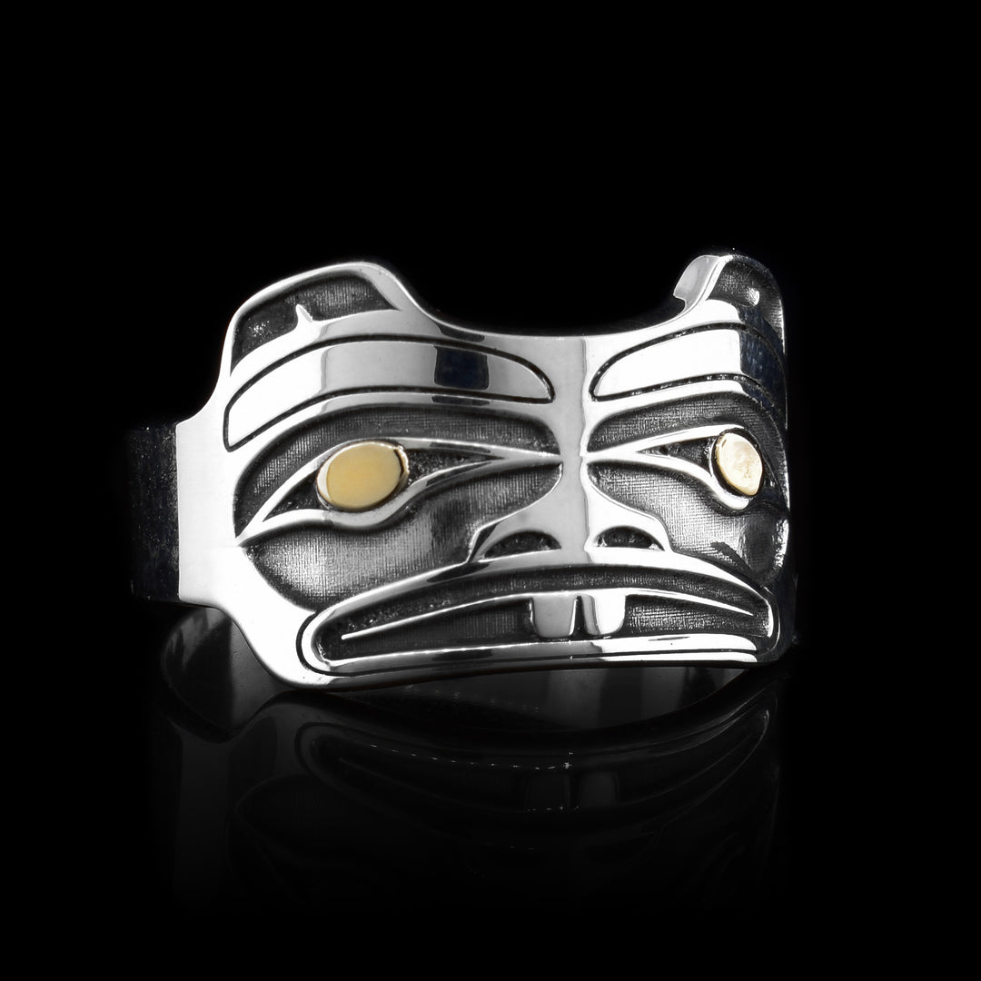 This gold and silver ring has been made using sterling silver and 14K gold and has a single band that becomes more wide at the top of it. There is a depiction of the head of the Beaver that has been cast into the surface of the wide portion of the ring. The designs are deep and the eyes of the Beaver are made using the gold.