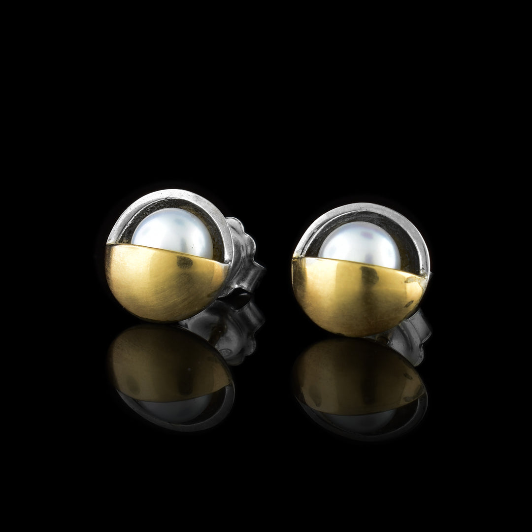 These pearl stud earrings have freshwater pearls laid in a sterling silver body with a 14K gold half circle covering half of each pearl.