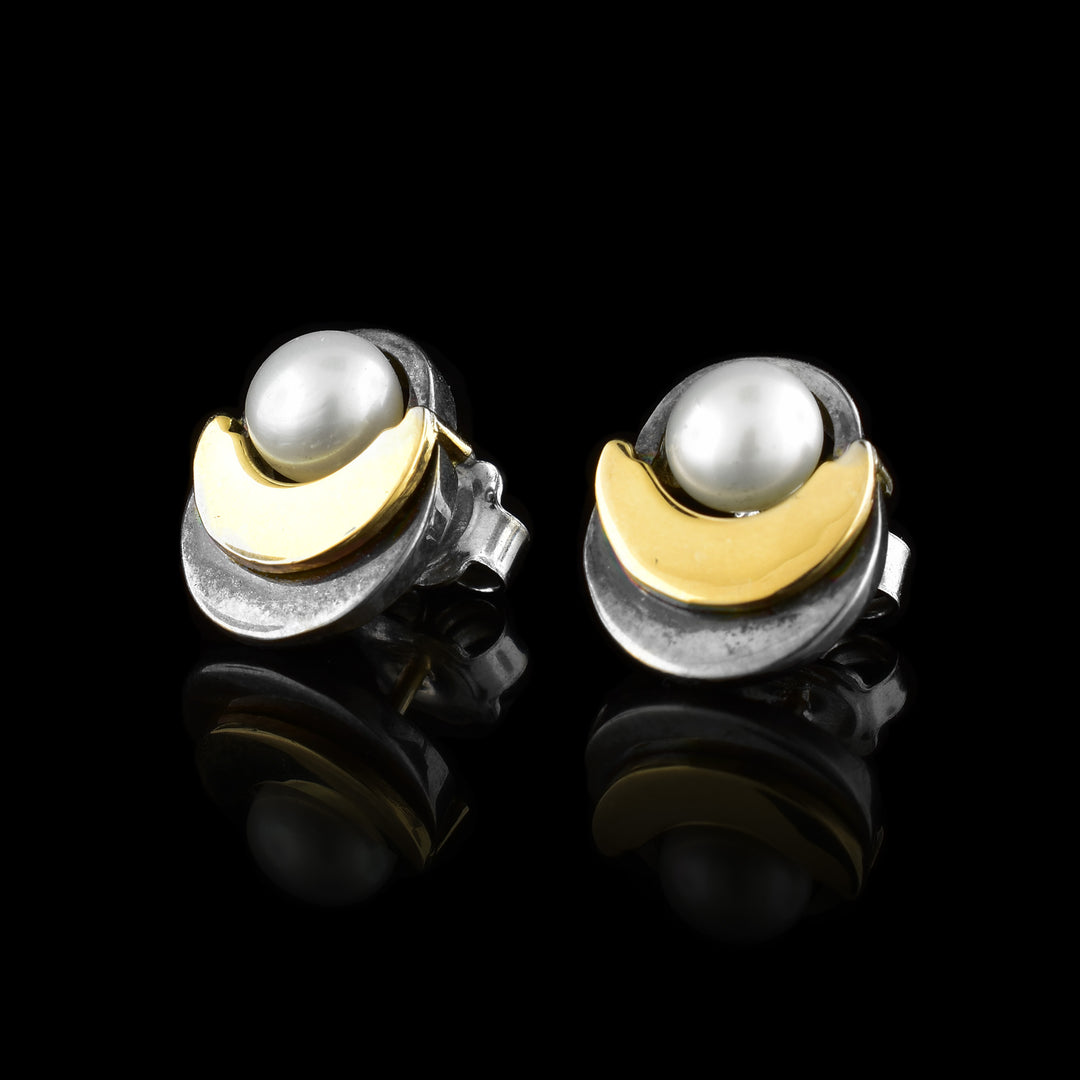 These pearl stud earrings have a sterling silver crescent going around a fresh water pearl with a smaller 14K gold crescent on top of the silver one.